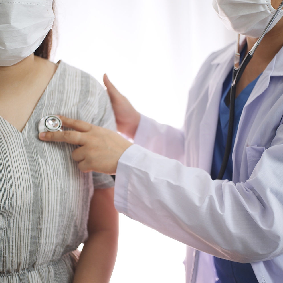 Female medicine doctor working on table with consulting patient, wearing mask to prevent viruses