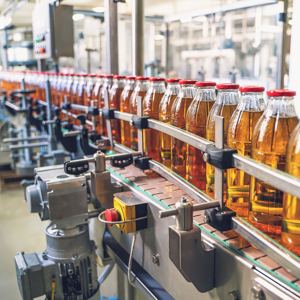 Conveyor belt, juice in glass bottles on beverage plant or factory interior, industrial manufacturing production line