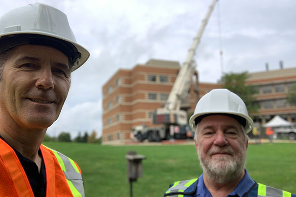 Two builders in front of a crane lift