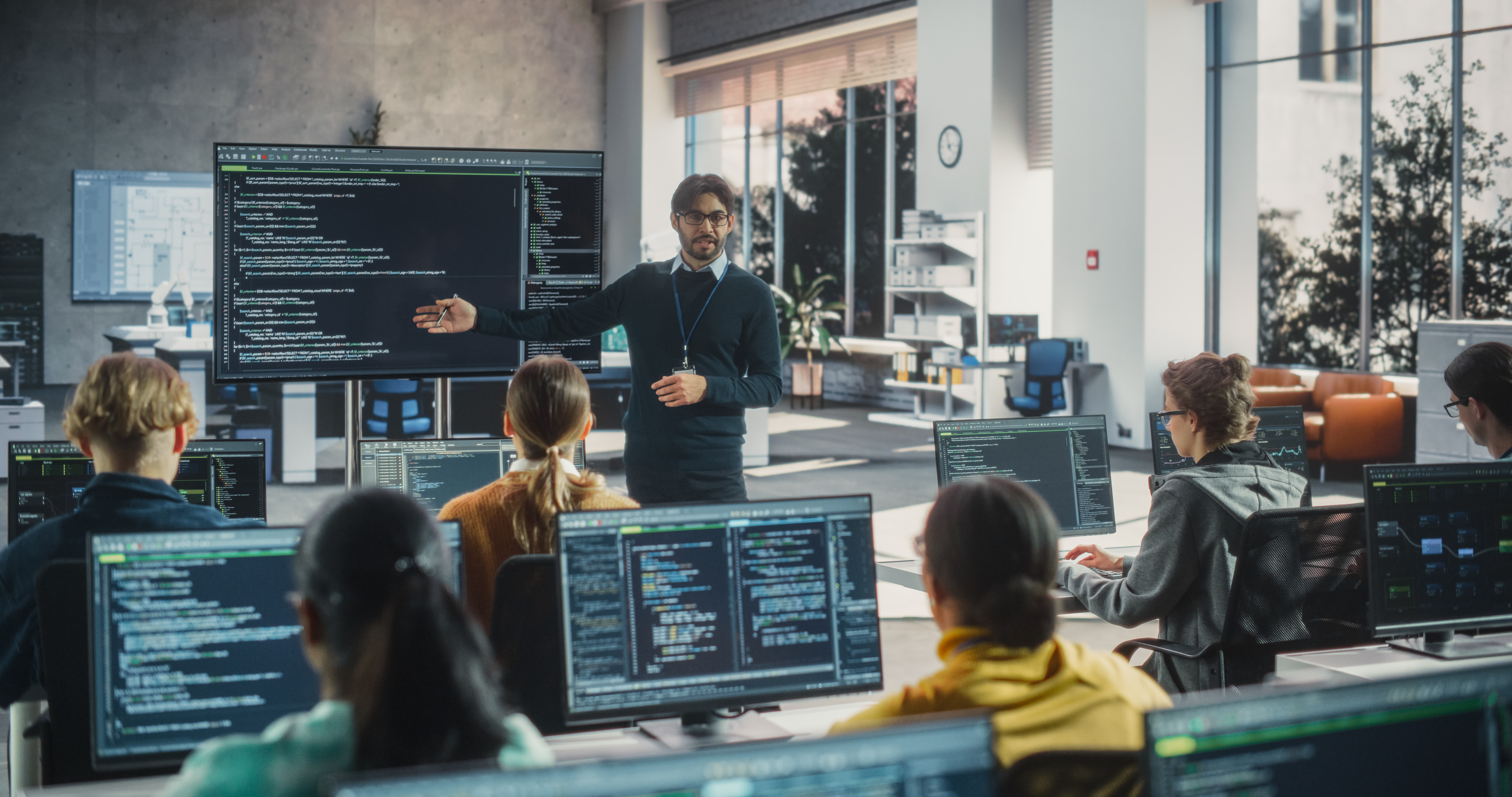 Knowledgeable Teacher Giving a Lecture About Software Engineering to a Group of Smart Diverse University Students. International Undergraduates Sitting Behind Desks with Computers